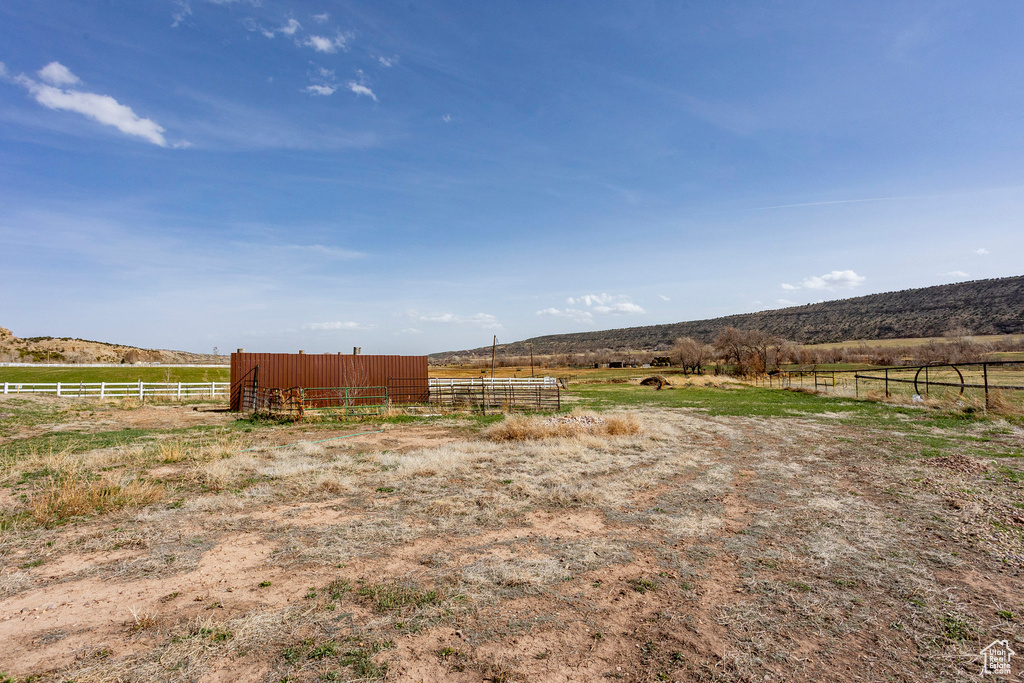 View of yard with fence, an outdoor structure, an outbuilding, and a rural view