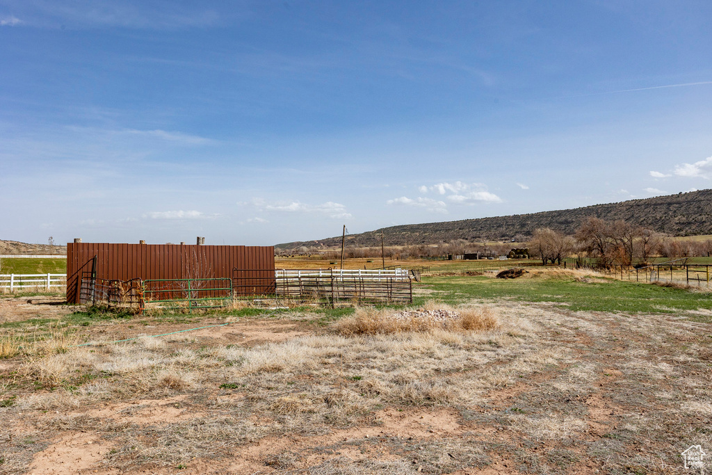 View of yard with a pole building, a rural view, fence, and an outbuilding