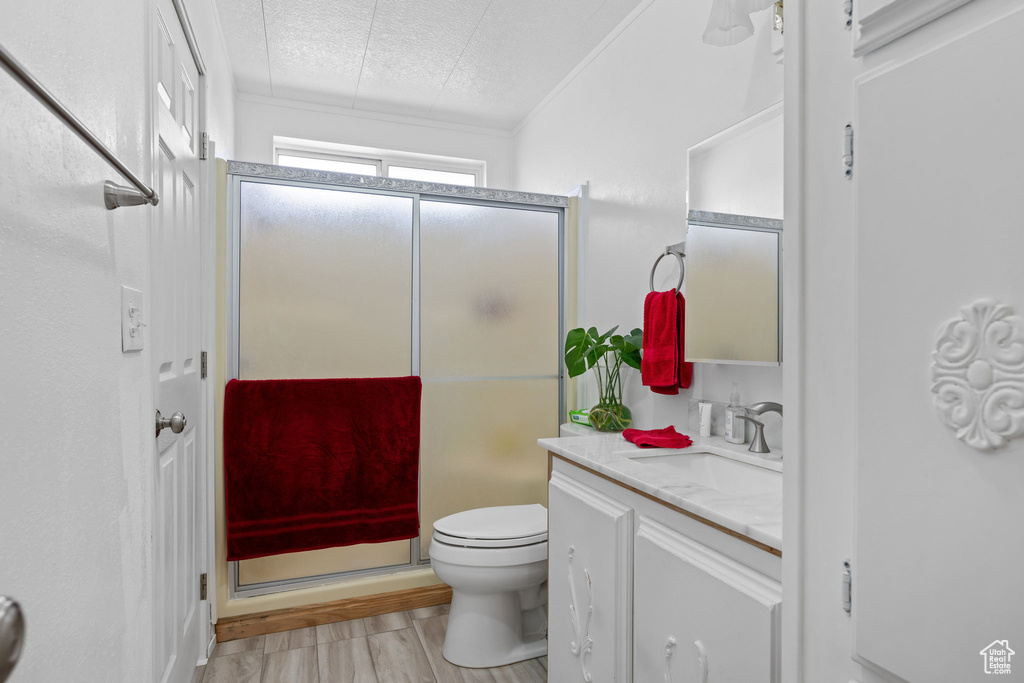 Full bath featuring vanity, toilet, a textured ceiling, a shower stall, and wood finished floors