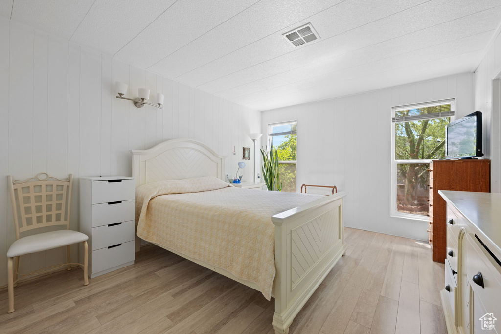 Bedroom featuring light wood-type flooring, visible vents, and multiple windows