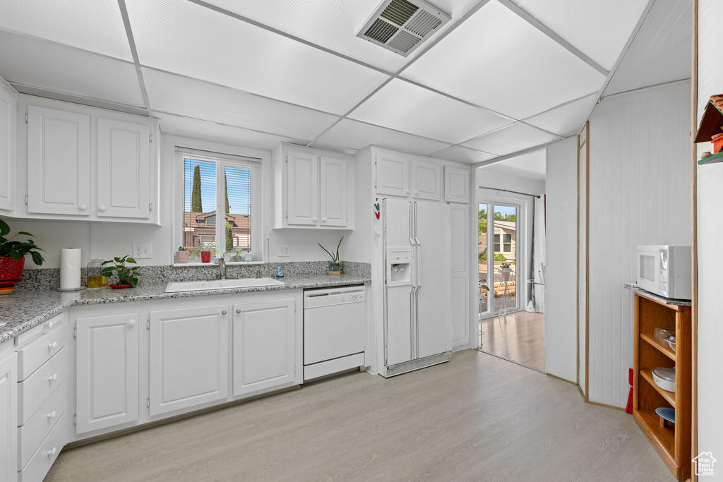 Kitchen featuring visible vents, white appliances, light wood-type flooring, white cabinetry, and a sink