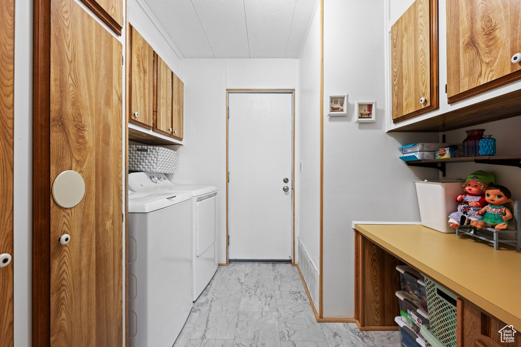 Laundry room featuring baseboards, marble finish floor, cabinet space, and washer and clothes dryer