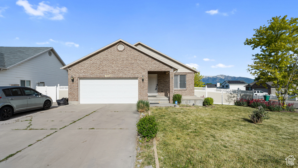 Single story home featuring brick siding, an attached garage, concrete driveway, and a mountain view