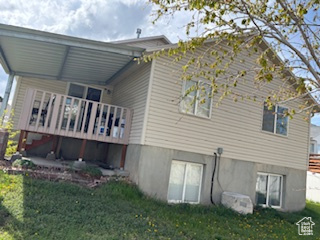 Back of property featuring a lawn and a deck