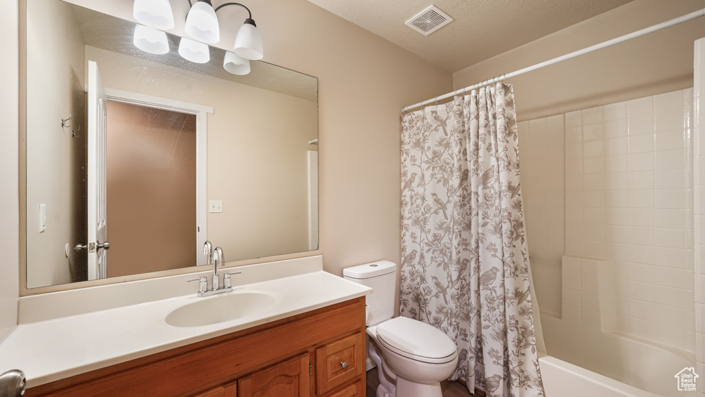 Bathroom featuring toilet, vanity, and shower / bath combo with shower curtain