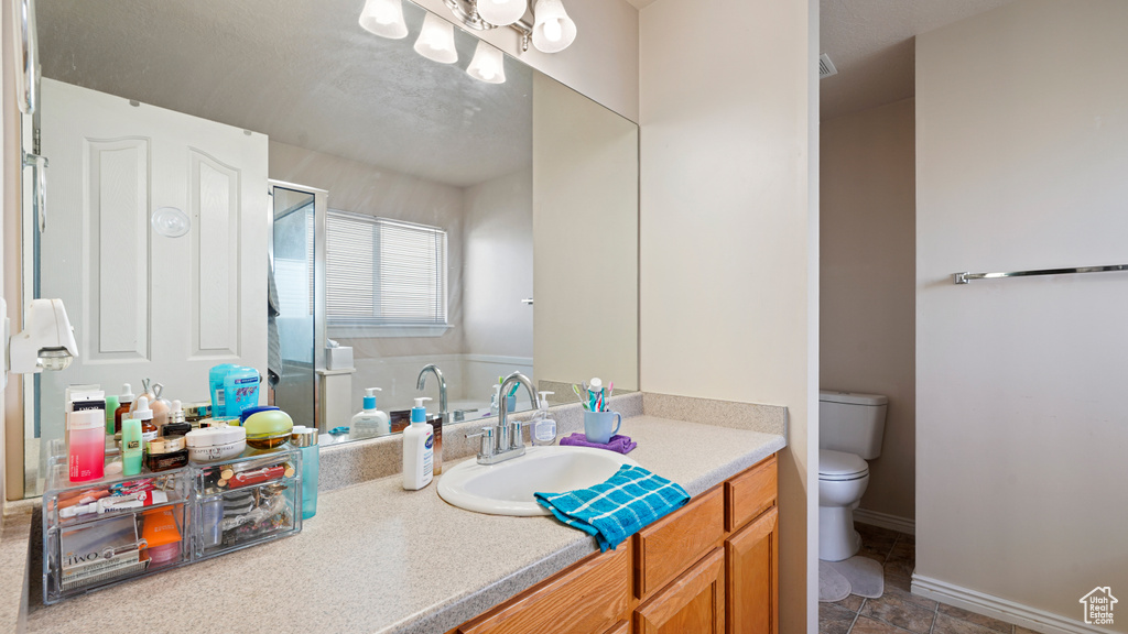 Bathroom featuring toilet, vanity, and a shower with door