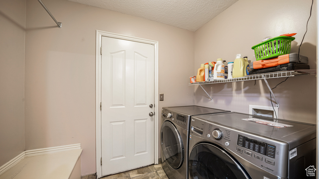 Washroom with washer and clothes dryer and a textured ceiling