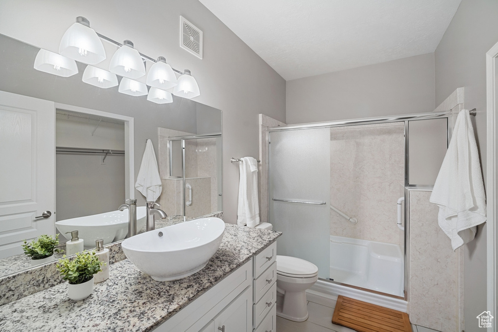 Bathroom featuring toilet, visible vents, a shower stall, and vanity