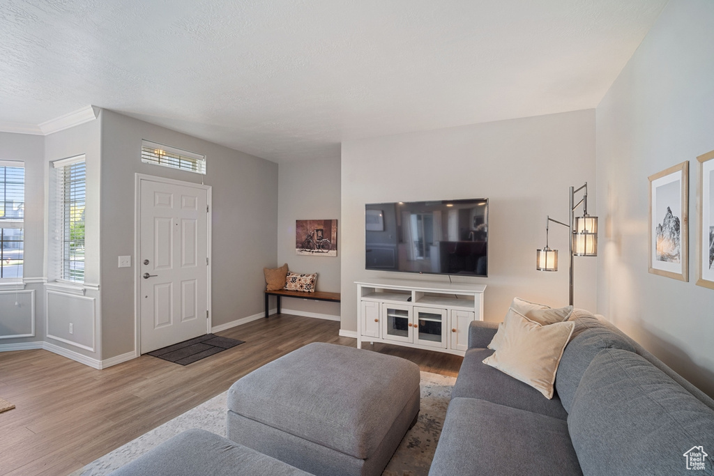 Living area with baseboards, ornamental molding, and wood finished floors