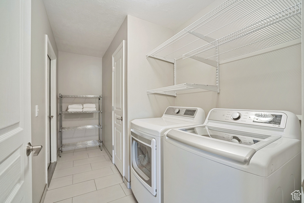 Laundry room featuring light tile patterned floors, laundry area, and washer and clothes dryer