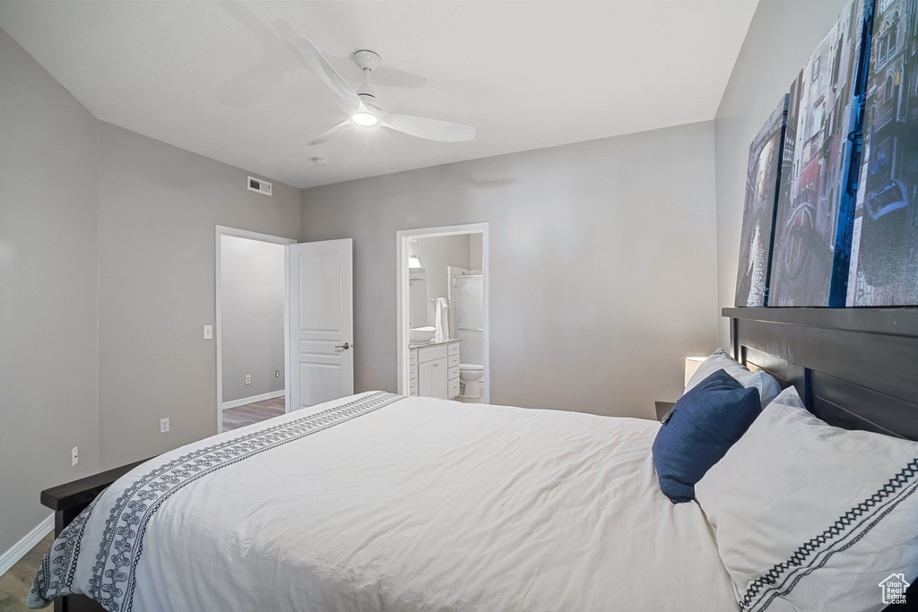Bedroom with ceiling fan, baseboards, wood finished floors, ensuite bathroom, and visible vents