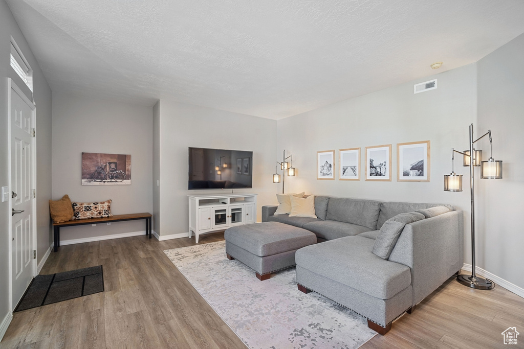 Living room featuring baseboards, visible vents, and wood finished floors