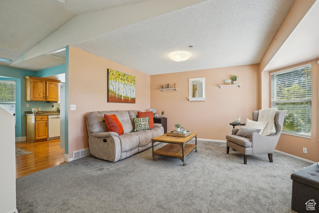 Living area featuring vaulted ceiling, a wealth of natural light, light colored carpet, and visible vents