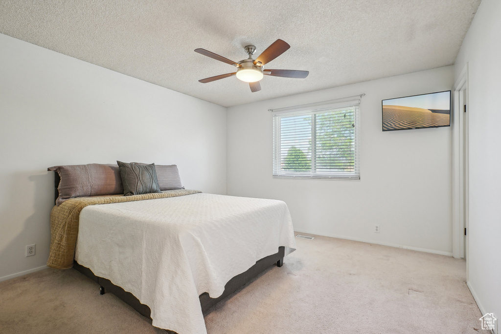 Bedroom featuring a textured ceiling, ceiling fan, and light colored carpet