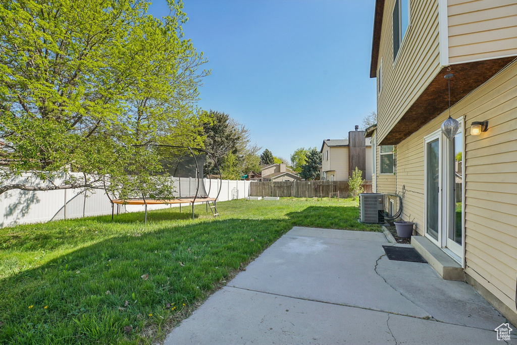 View of yard with a patio, central AC unit, a fenced backyard, and a trampoline