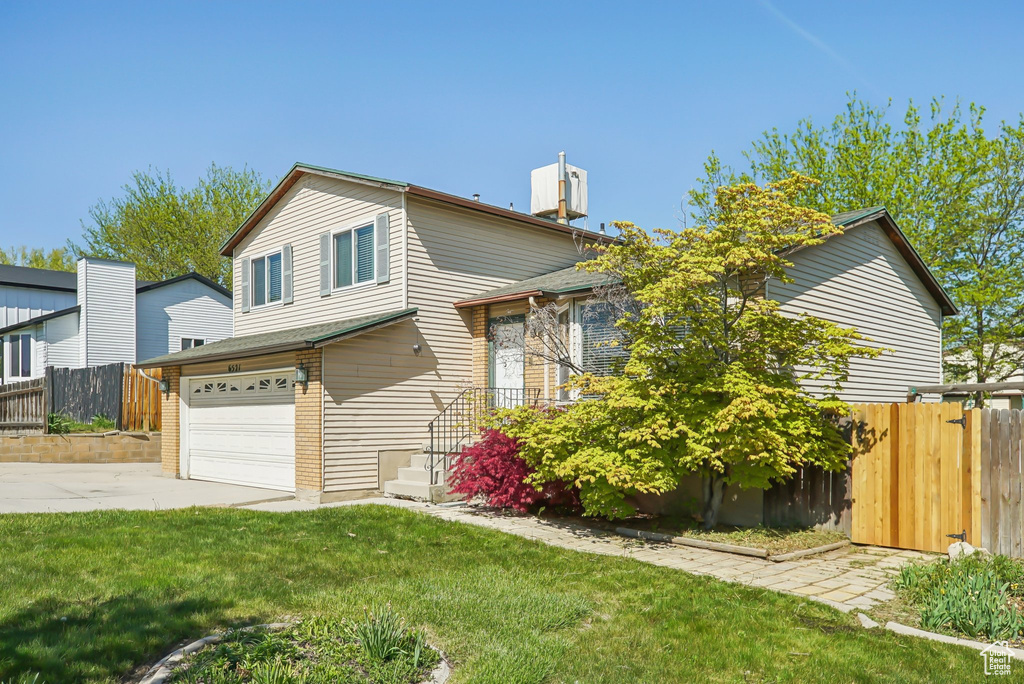 View of front of house with an attached garage, fence, a front yard, and concrete driveway