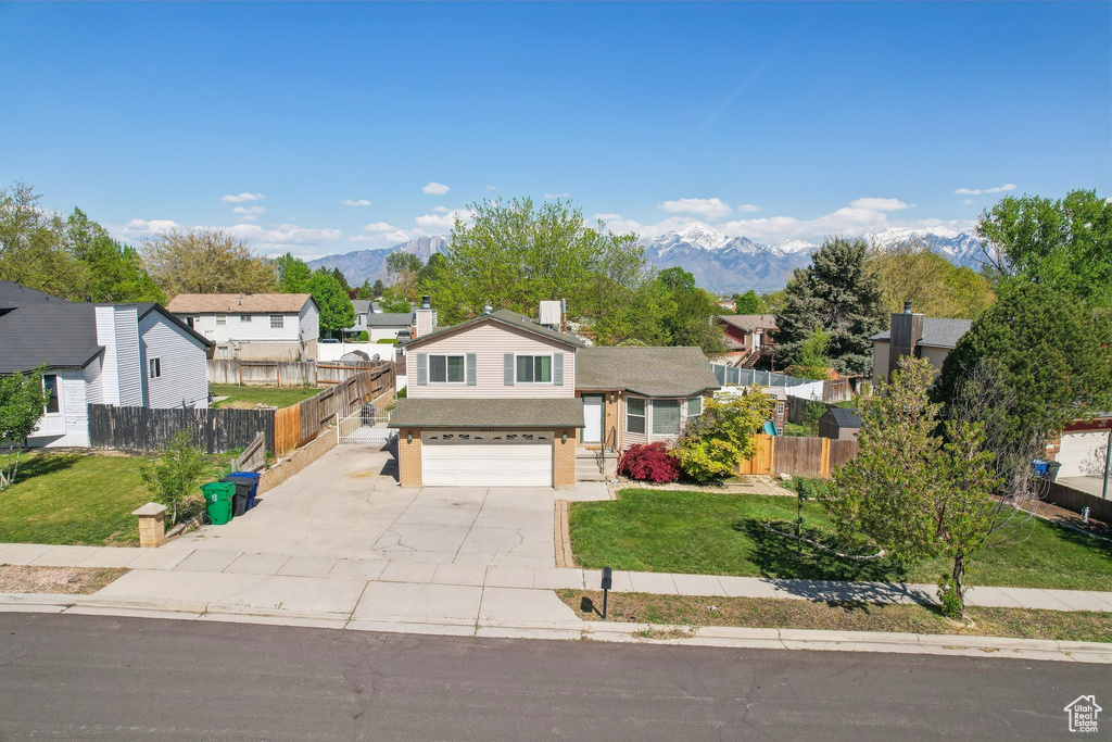 Tri-level home featuring a garage, fence, a mountain view, and concrete driveway