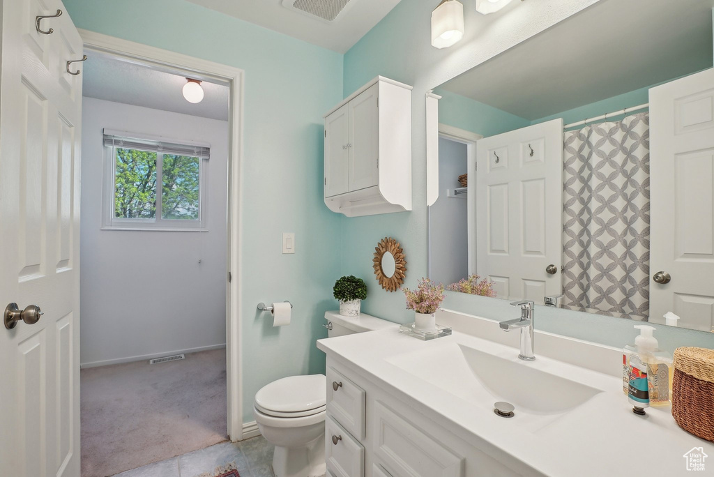 Bathroom featuring vanity, baseboards, visible vents, and toilet
