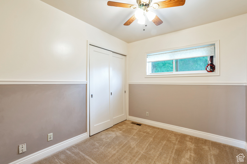 Unfurnished bedroom with ceiling fan, light carpet, baseboards, visible vents, and a closet