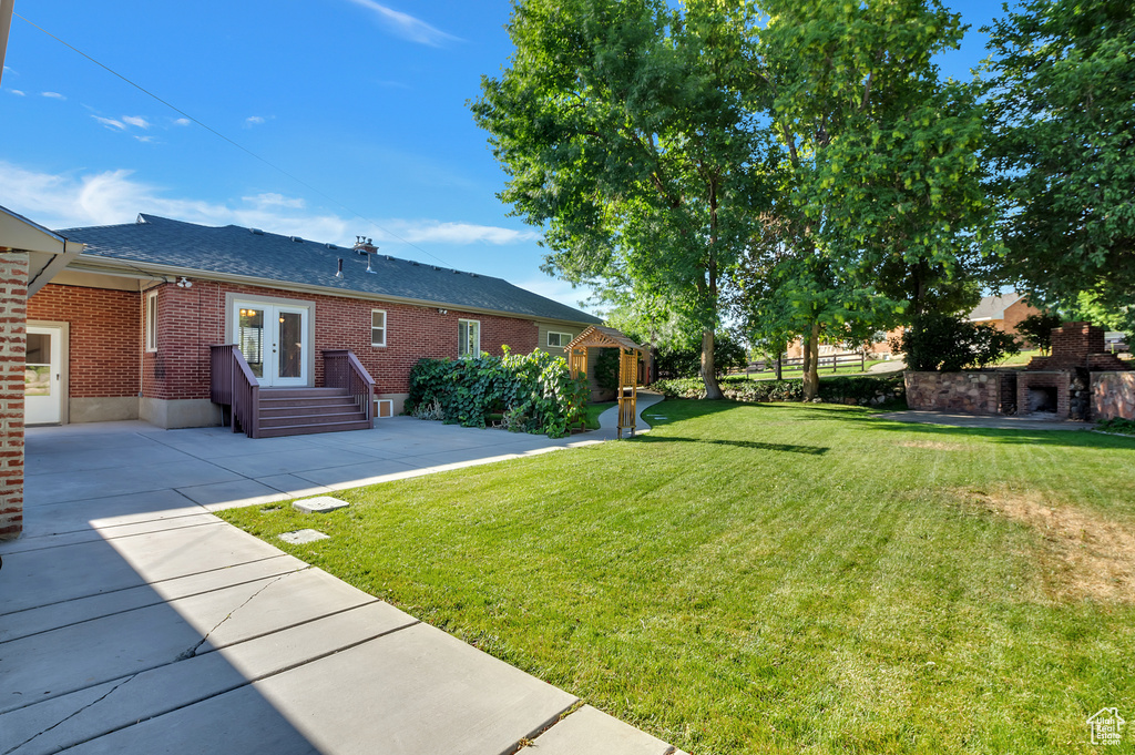 View of yard with french doors, a storage unit, a patio, and an outbuilding