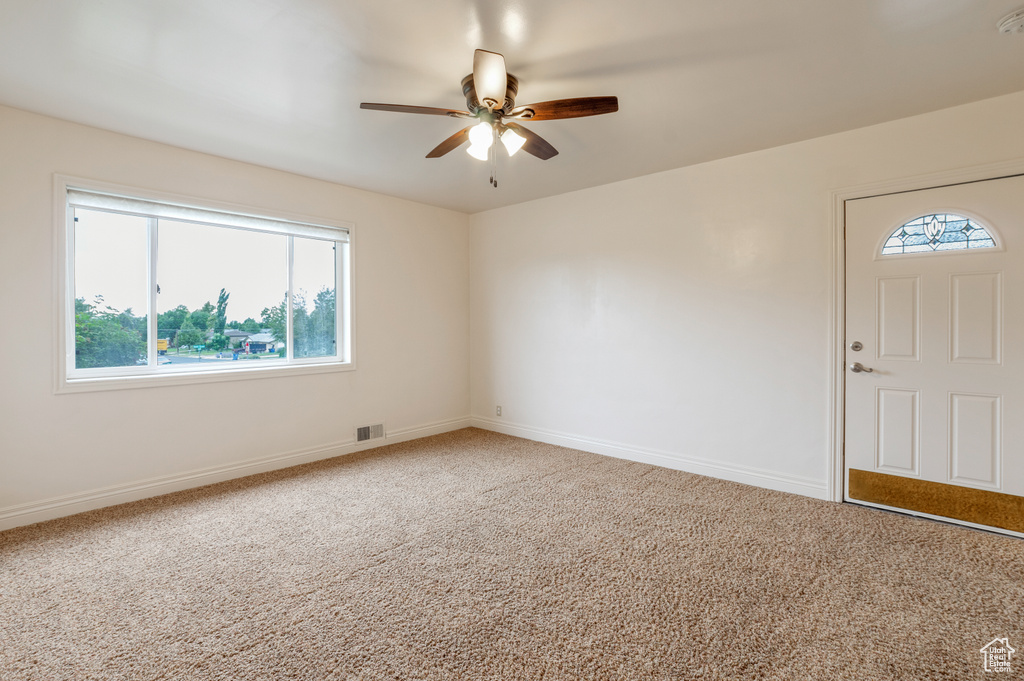 Empty room with carpet floors, baseboards, a ceiling fan, and visible vents