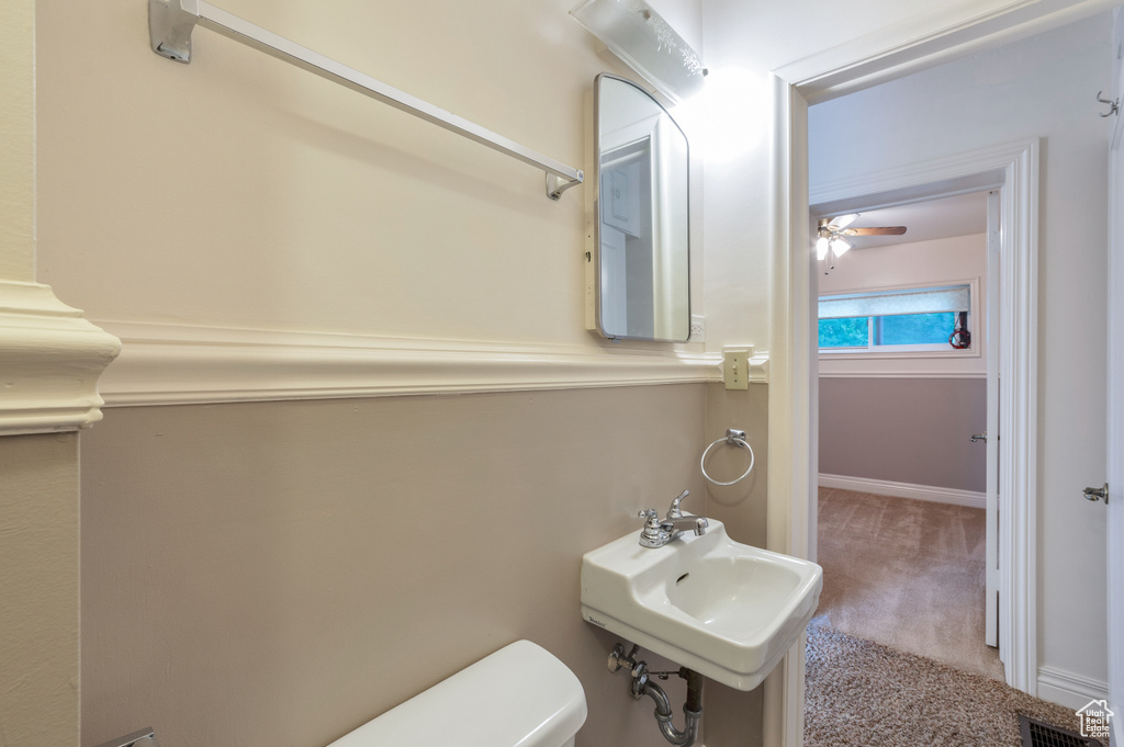 Bathroom featuring toilet, a ceiling fan, visible vents, and a sink