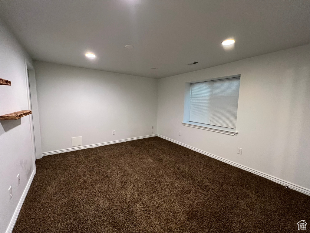 Empty room featuring dark carpet, recessed lighting, baseboards, and visible vents