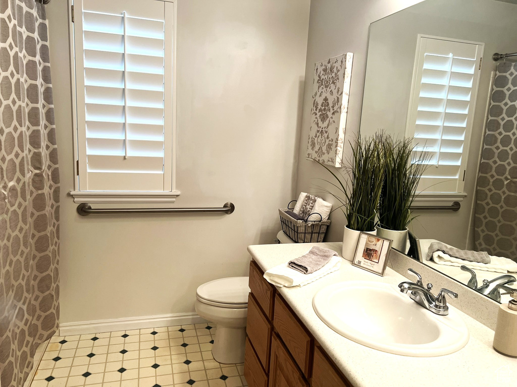 Bathroom featuring toilet, vanity, curtained shower, tile patterned floors, and baseboards