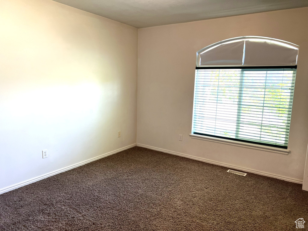 Carpeted empty room featuring baseboards and visible vents