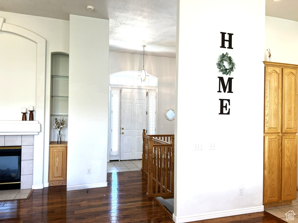 Interior space with a tiled fireplace, baseboards, built in shelves, and hardwood / wood-style flooring