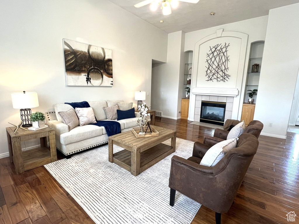 Living area featuring wood-type flooring, baseboards, a ceiling fan, and a tiled fireplace