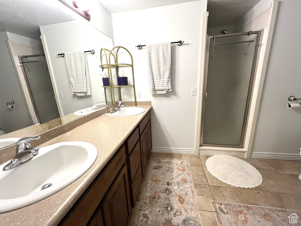 Bathroom featuring double vanity, tile patterned floors, a sink, and a stall shower