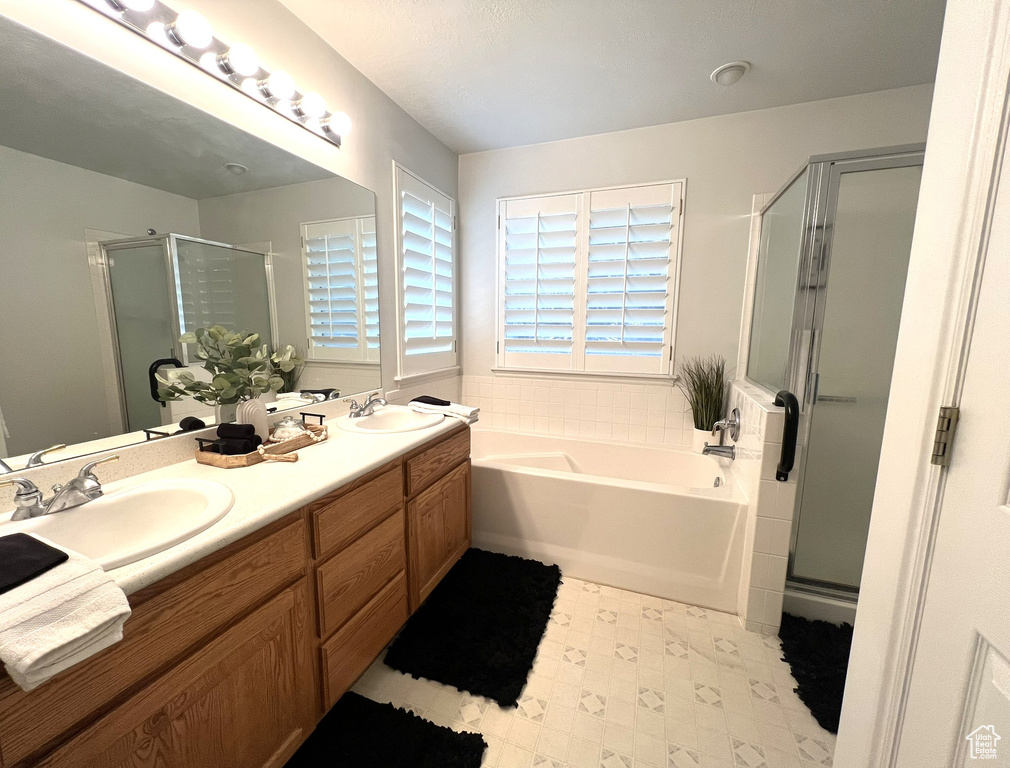 Bathroom with double vanity, a bath, a stall shower, and a sink