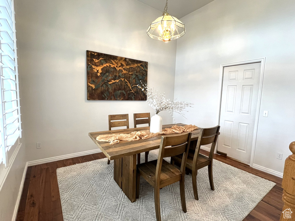 Dining area featuring a high ceiling, baseboards, a notable chandelier, and wood finished floors