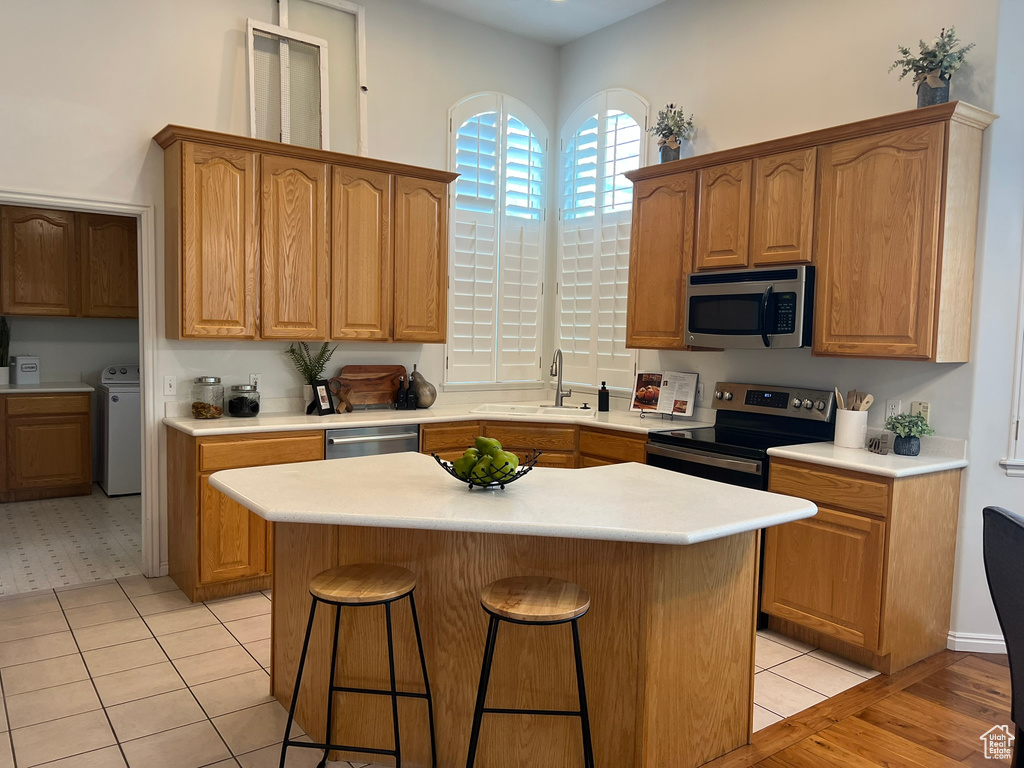 Kitchen with stainless steel appliances, a kitchen bar, light countertops, and washer / dryer