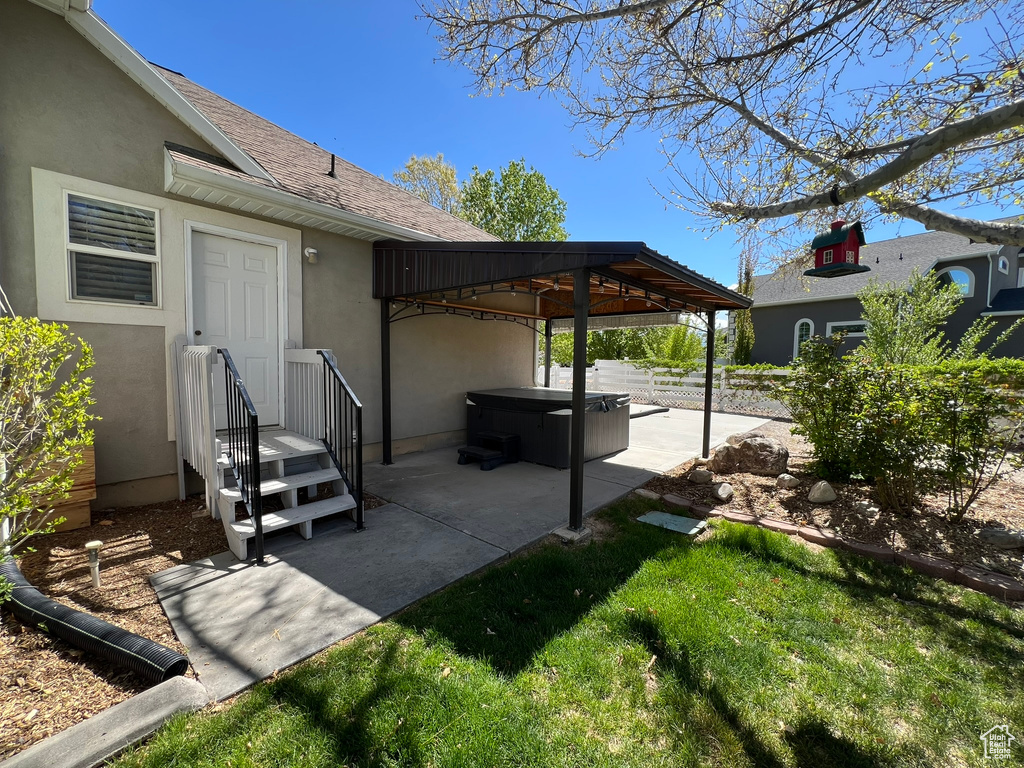 View of patio featuring fence, a gazebo, and a hot tub
