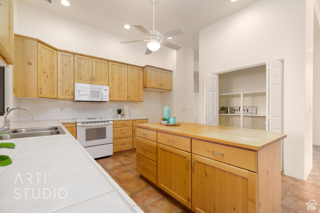 Kitchen with a sink, white appliances, a ceiling fan, tasteful backsplash, and butcher block counters