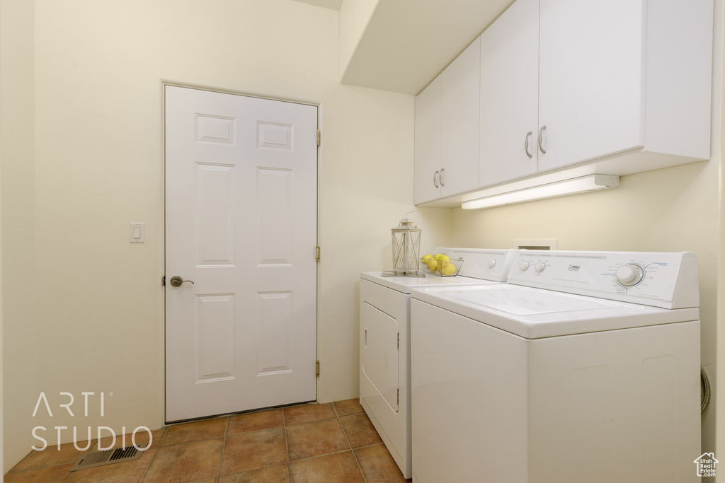 Washroom with cabinet space, separate washer and dryer, and visible vents