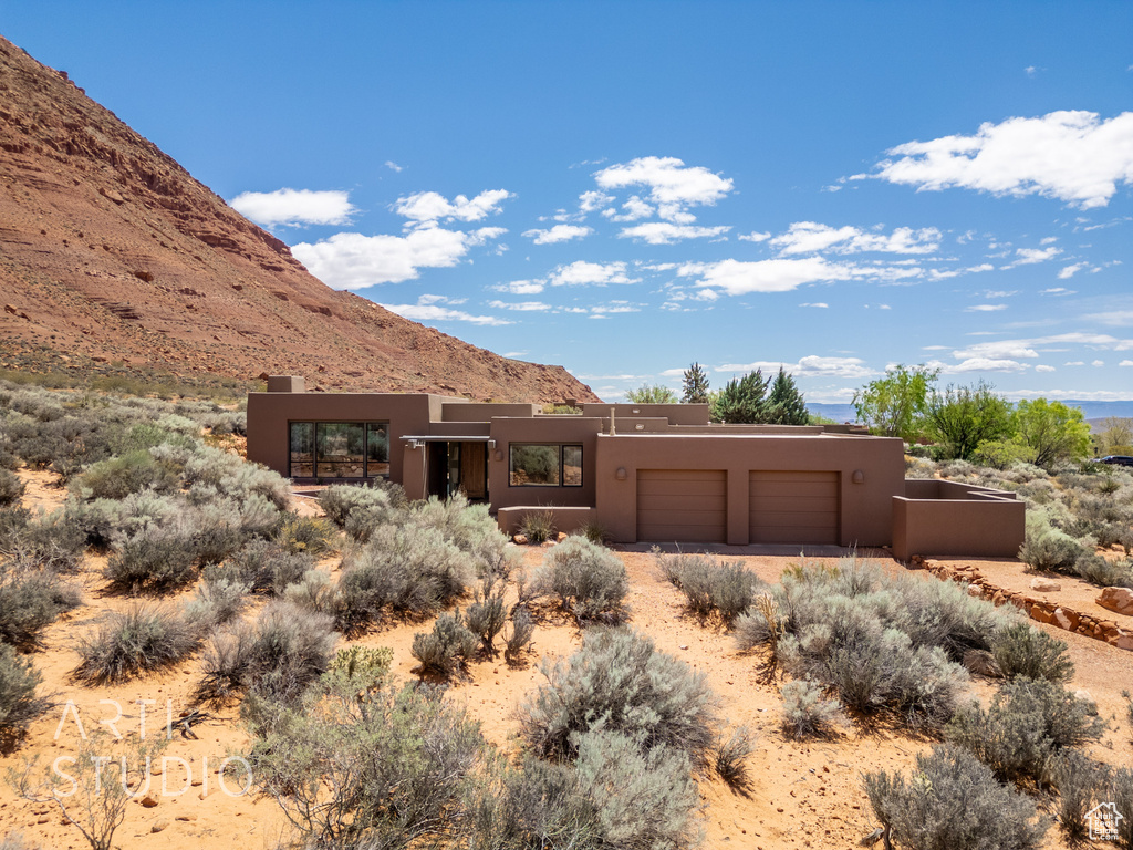Adobe home featuring a garage, a mountain view, stucco siding, and dirt driveway
