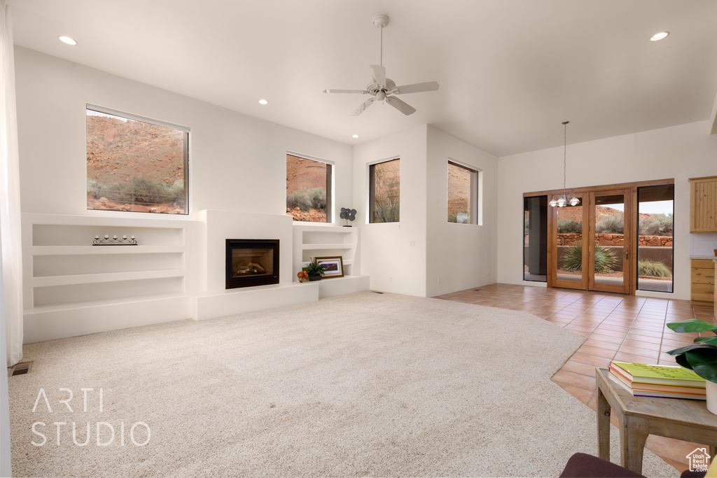 Living room featuring carpet floors, a glass covered fireplace, built in shelves, ceiling fan with notable chandelier, and recessed lighting