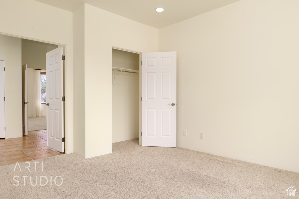 Unfurnished bedroom featuring recessed lighting, carpet flooring, tile patterned floors, and a closet