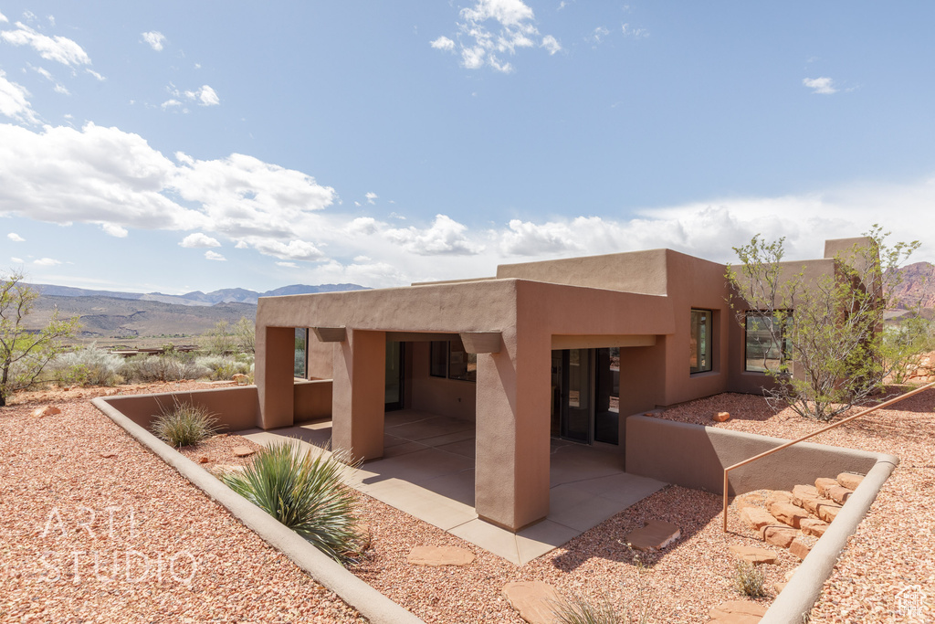 Rear view of house with a patio area, stucco siding, and a mountain view