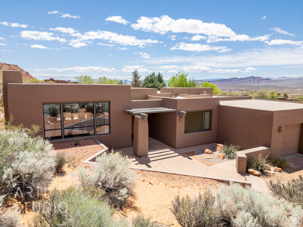 Back of house featuring a garage, a mountain view, and stucco siding