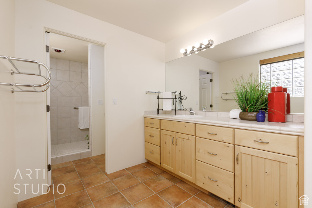 Bathroom featuring tiled shower and vanity