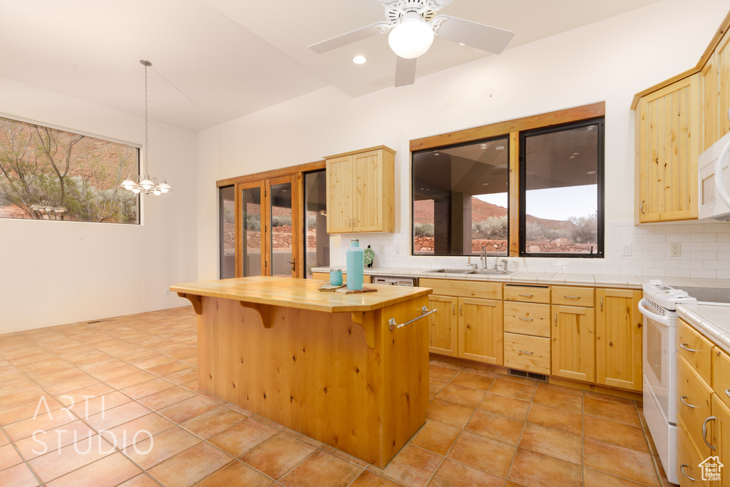 Kitchen with a kitchen breakfast bar, tasteful backsplash, white electric range, a sink, and light brown cabinets