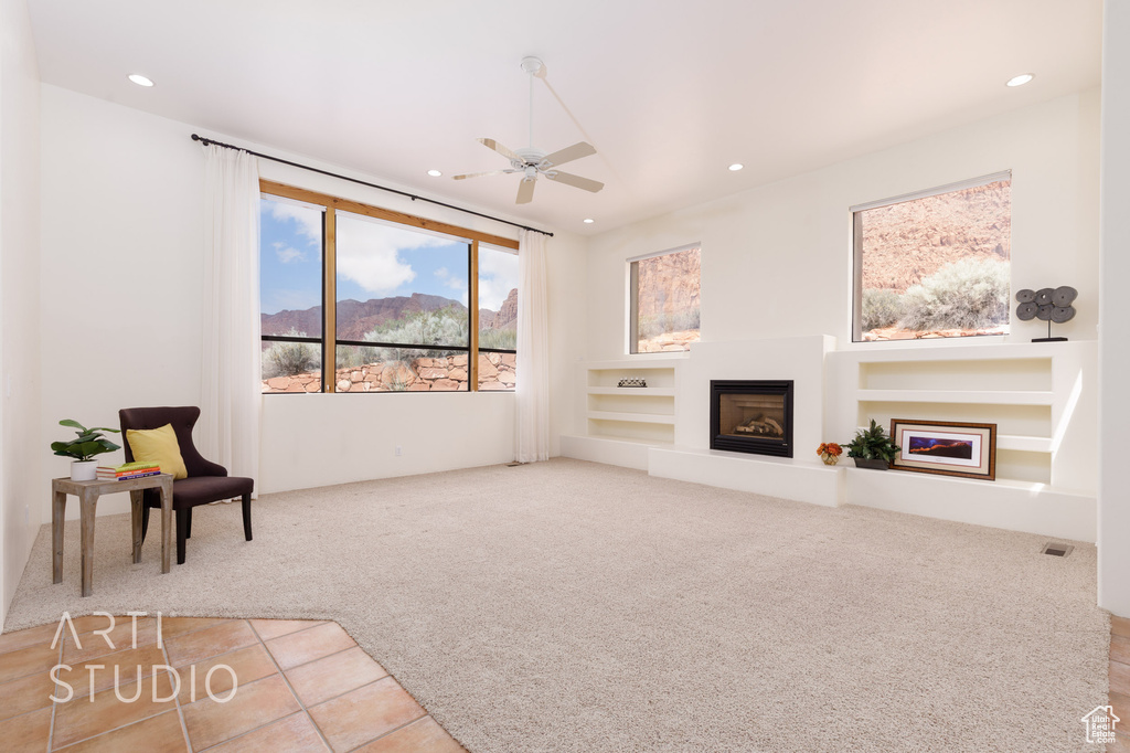 Unfurnished living room featuring ceiling fan, carpet floors, a glass covered fireplace, built in features, and recessed lighting