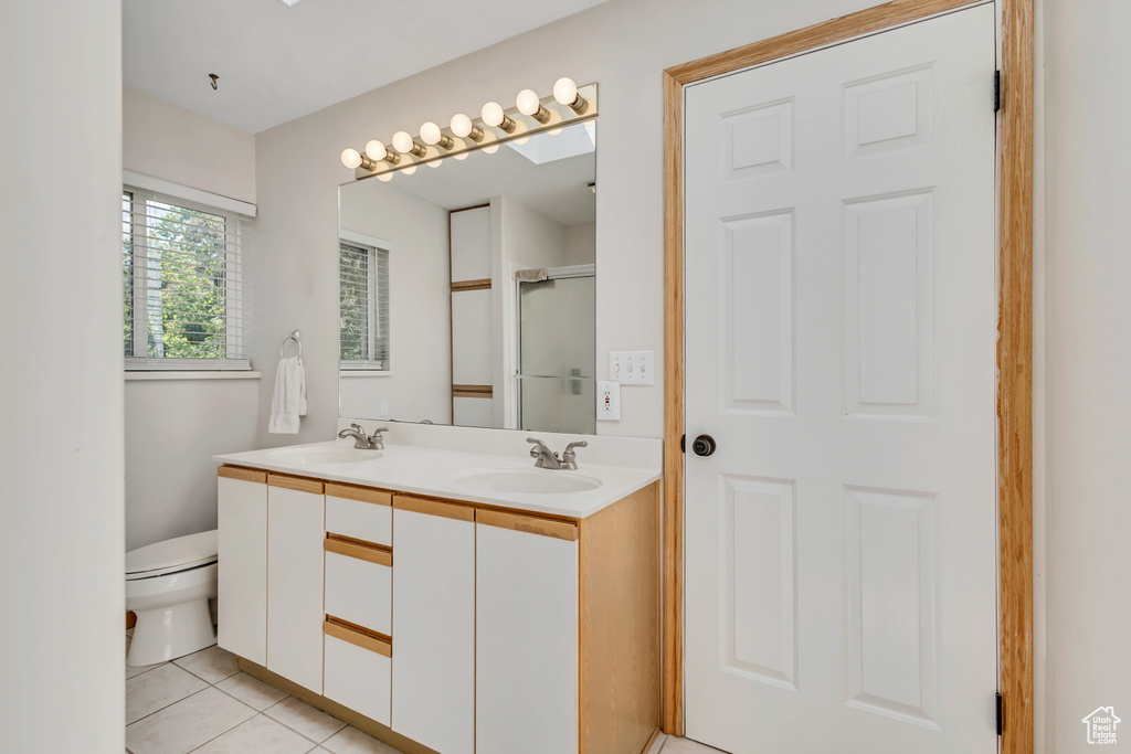 Full bath featuring double vanity, a sink, tile patterned floors, and toilet