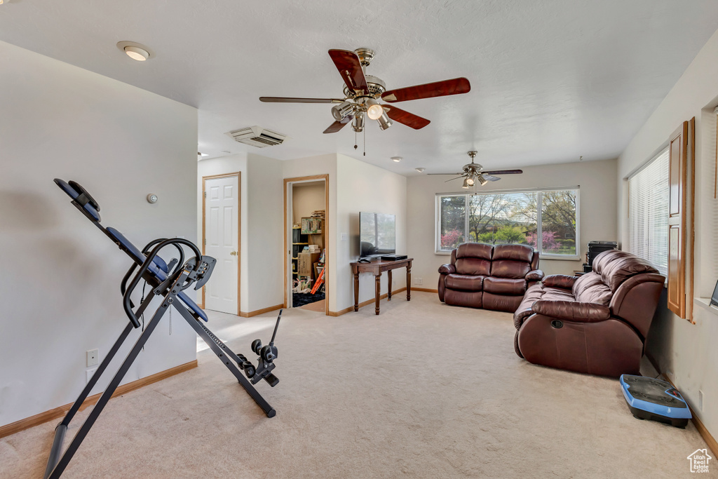 Workout room with light colored carpet, a ceiling fan, and baseboards