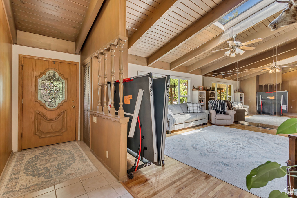 Foyer entrance featuring ceiling fan, wooden ceiling, and vaulted ceiling with skylight