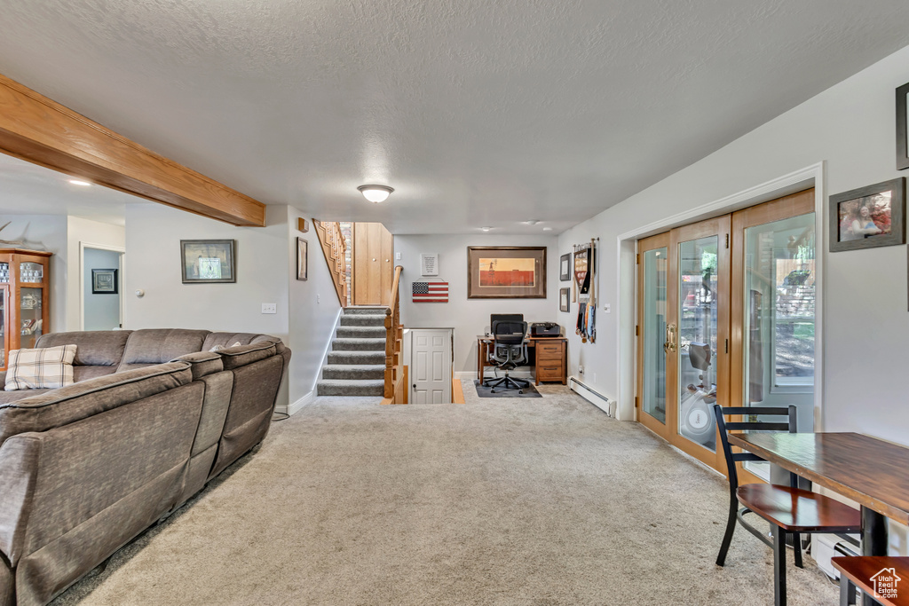 Carpeted living room with a textured ceiling, stairs, baseboards, a baseboard radiator, and beamed ceiling